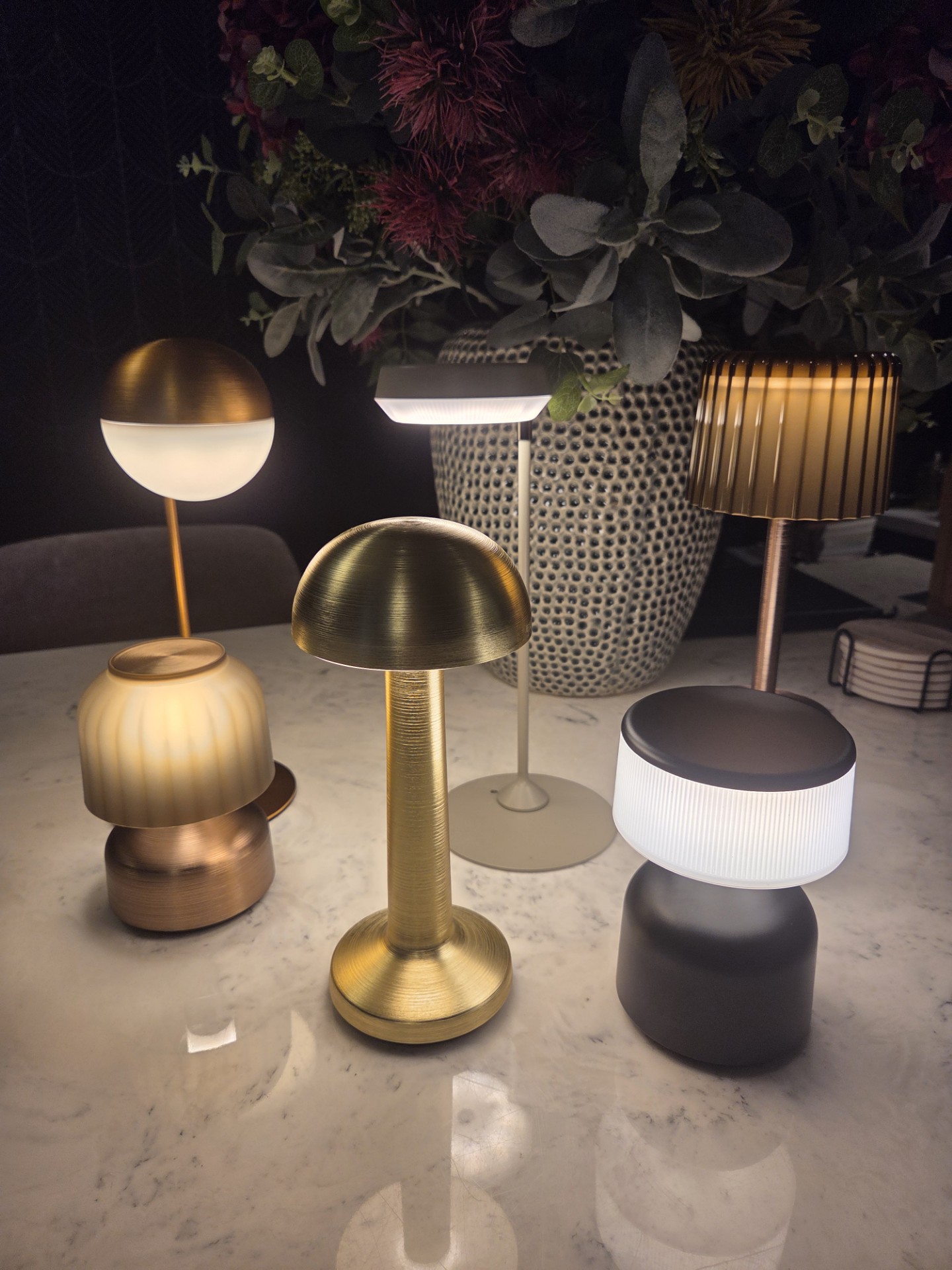 A selection of glowing cordless table lights in brass, grey and bronze finishes